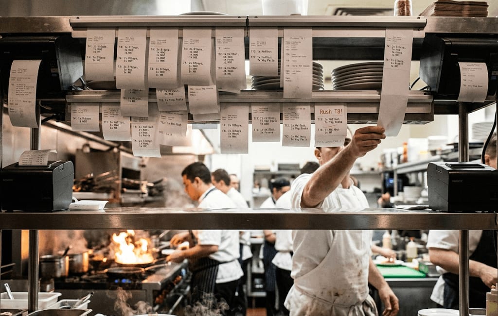 Kitchen tickets stacking up on a rail during a busy service