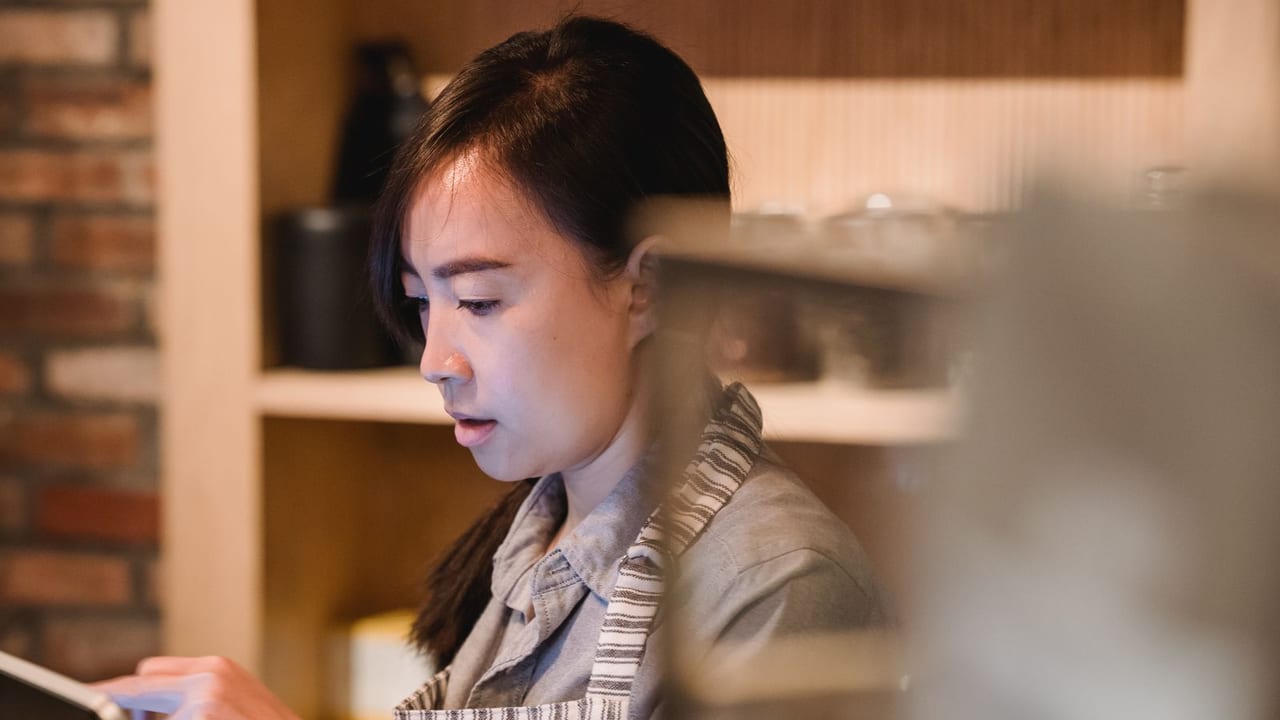 Bakery staff member working beside the pastry case.