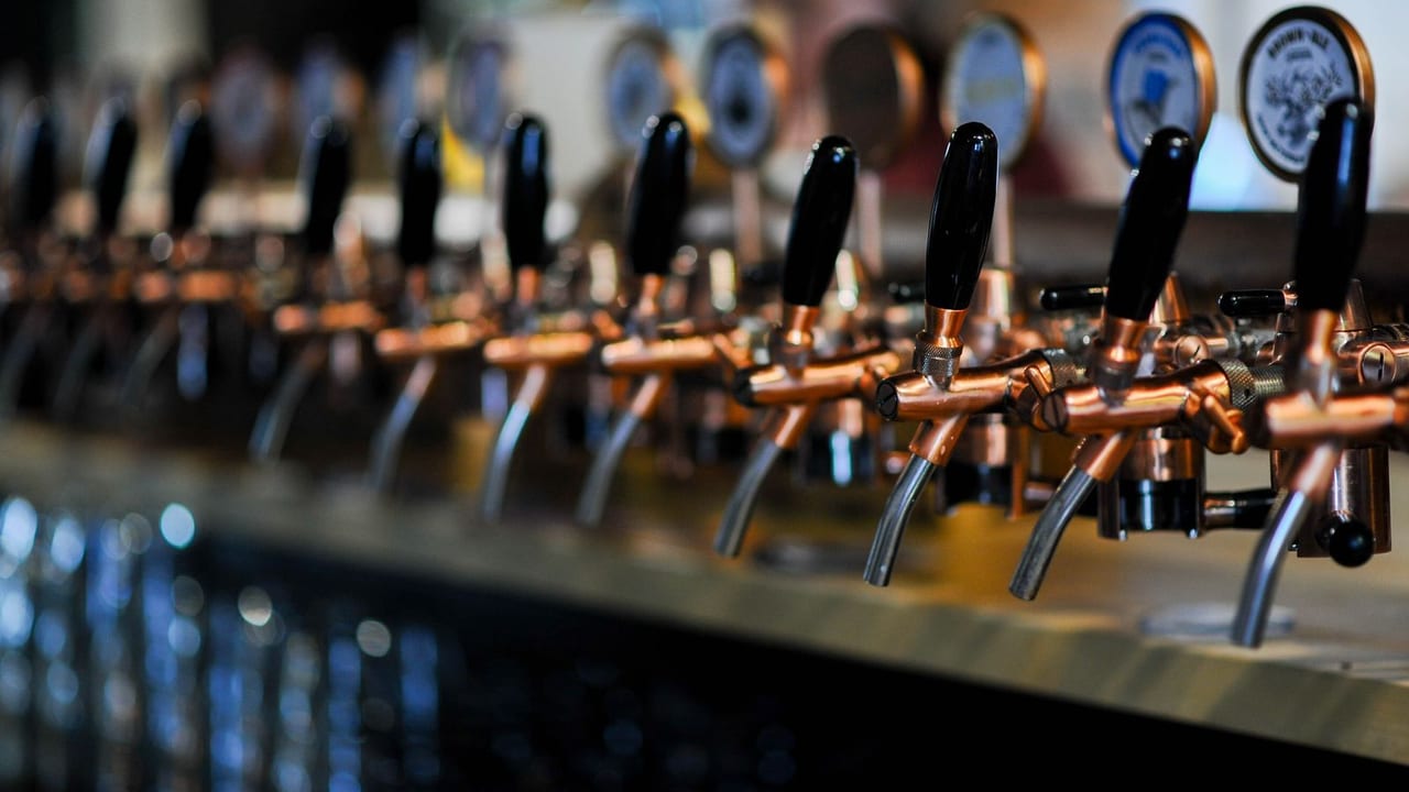 A row of beer taps along a taproom bar.