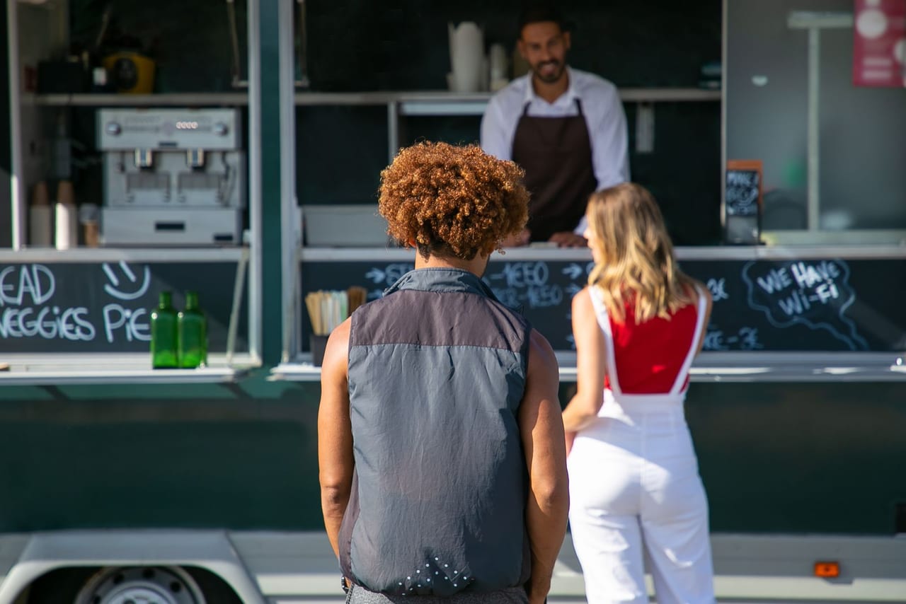 Customers ordering at a food truck service window.