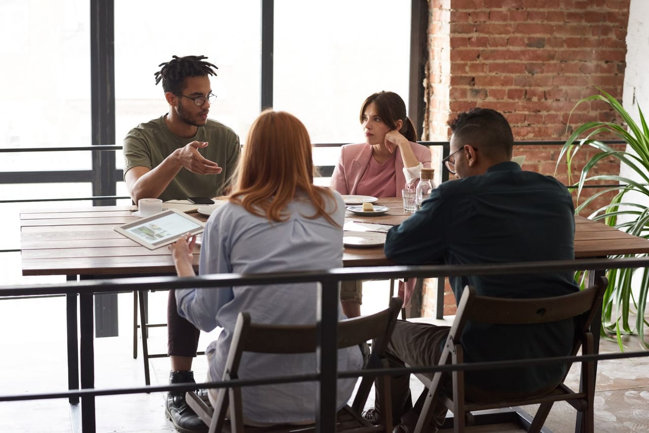 Restaurant group team meeting around a table, reviewing figures on a tablet.