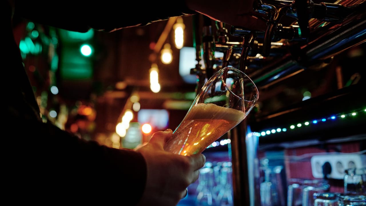 Bartender filling a glass of beer behind the bar.