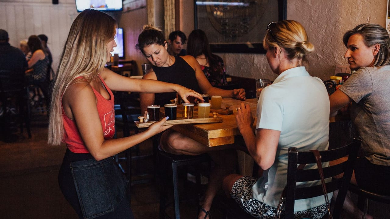 Server delivering a round of drinks to a table of guests.